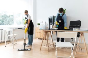 Two people from a home cleaning service vacuuming a room, focused on tidying up the space.