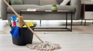 A bucket filled with cleaning supplies and a mop placed on the floor, representing a home cleaning service setup.