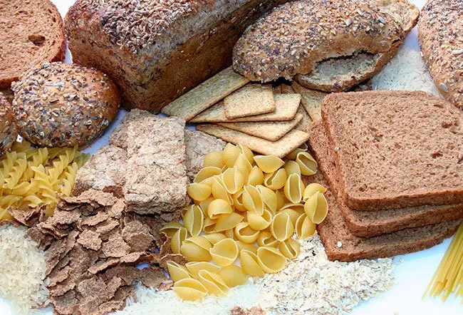 Assorted baked goods and dry pantry staples (loaves, crackers, pasta, and flour) arranged on a white surface.