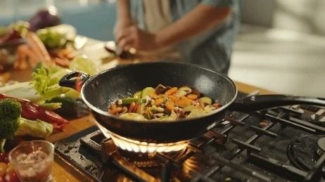 Cast iron cookware cooking fresh vegetables over an open flame