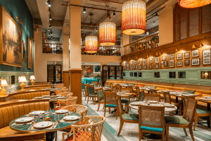 Elegant Kolkata restaurant interior with wooden tables, upholstered seating, warm pendant lights, and decorative wall artwork.