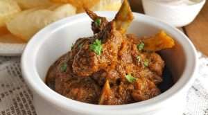 Spicy Indian mutton curry with potato pieces served in a white bowl