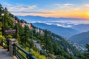 Scenic view of Mussoorie hill station in Uttarakhand, India, featuring lush green hills, hillside houses, winding roads, misty mountain ranges, and a beautiful golden sunset.